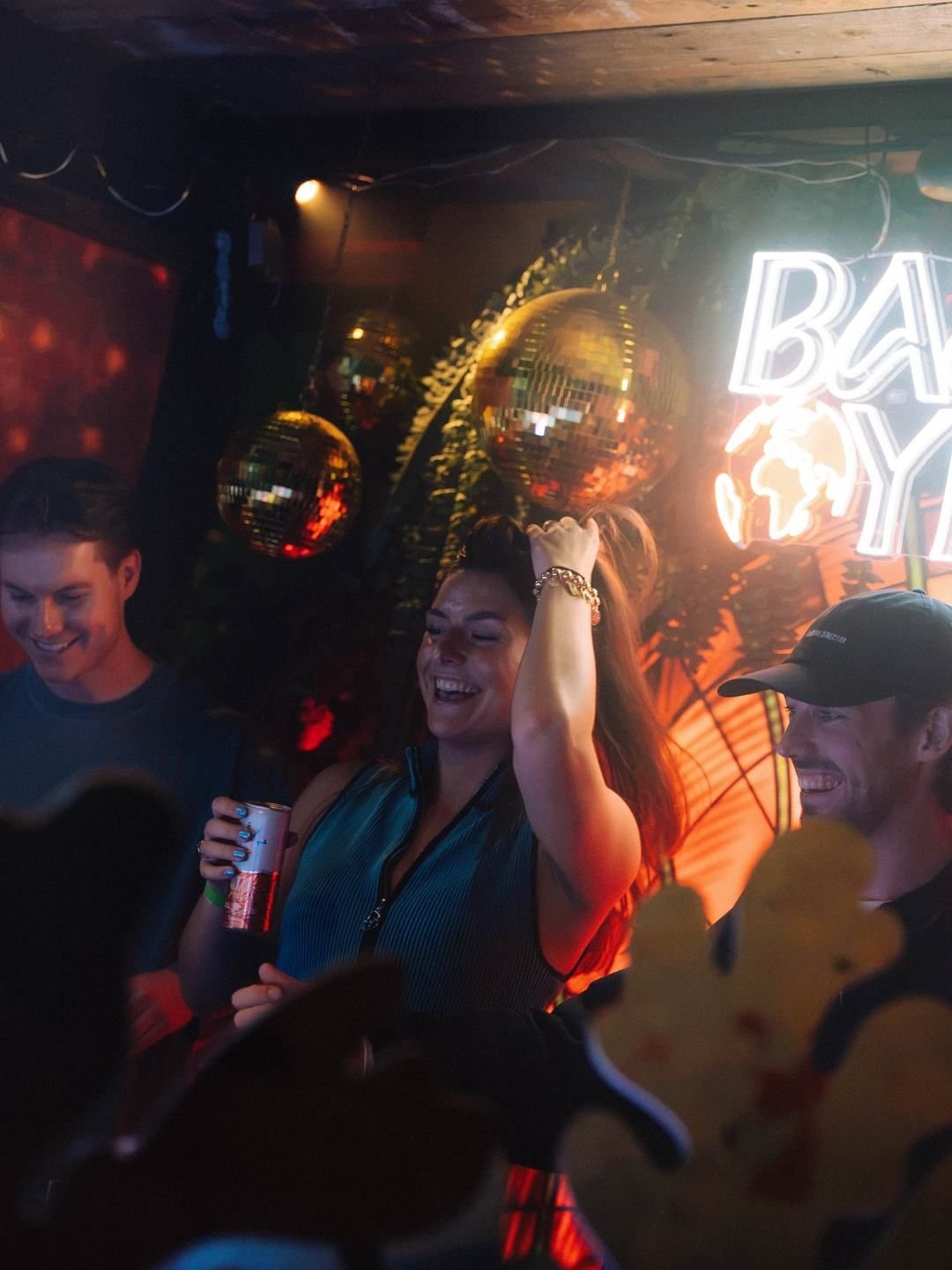 Guests laughing in front of the neon sign and disco balls at LouLou, Eindhoven