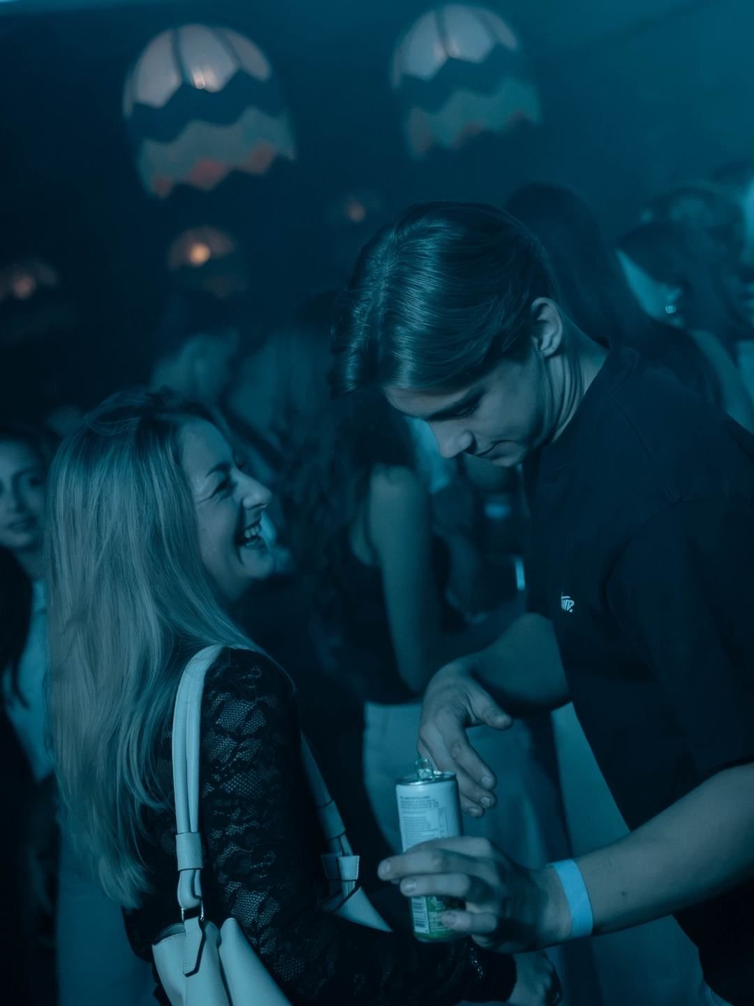 Crowd laughing and dancing in blue light at LouLou, Eindhoven
